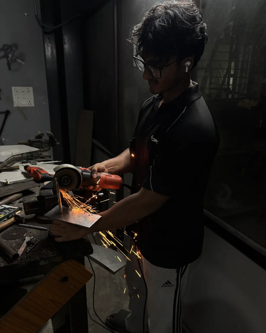Ranbir working with an angle grinder in a robotics workshop
